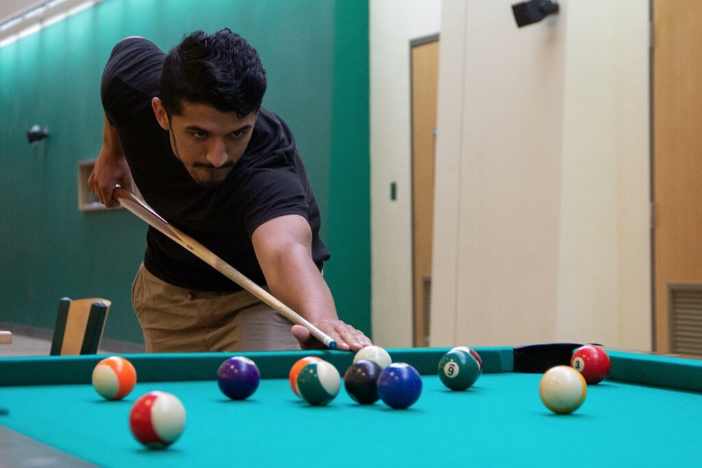 young person playing billiards